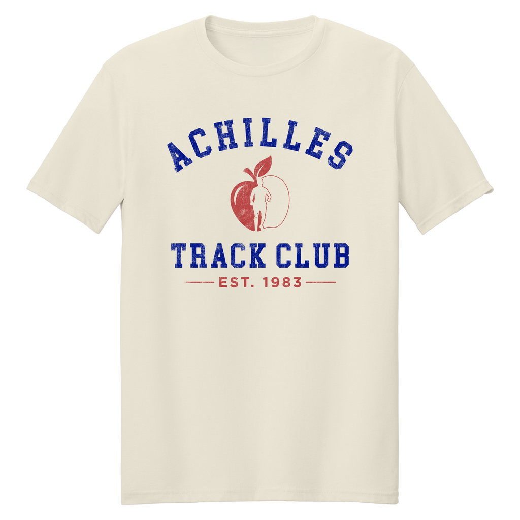 A cream short-sleeve t-shirt with a graphic on the chest reading 'ACHILLES TRACK CLUB' in blue, featuring a red apple illustration and running silhouette and 'EST. 1983' underneath.