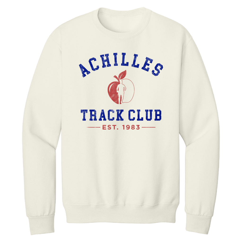An cream crewneck sweatshirt featuring a graphic on the front with the text 'ACHILLES TRACK CLUB' and 'EST. 1983' in blue, alongside a red apple graphic containing a running silhouette.