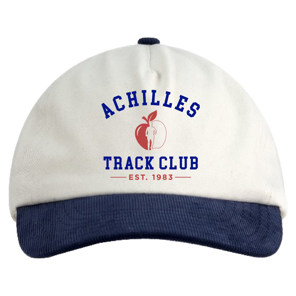 A baseball cap with an cream crown and a navy blue ribbed brim. The front features a navy blue arched 'ACHILLES' text above a red apple graphic with a persons silhouette, and 'TRACK CLUB' and 'EST.1983'