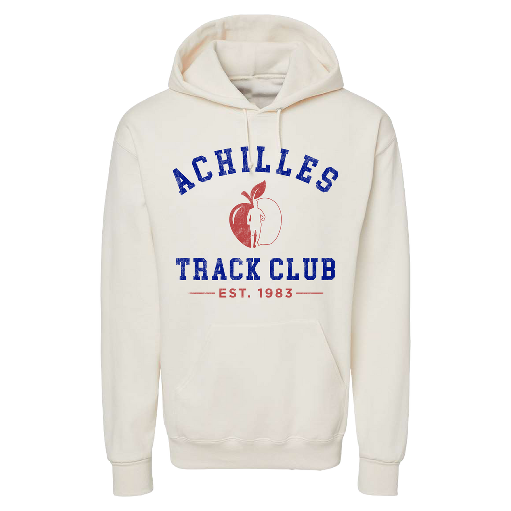 A cream pullover hoodie featuring a collegiate-style graphic on the chest that reads 'ACHILLES TRACK CLUB' in blue, with a red apple graphic and a running silhouette and 'EST. 1983' below.